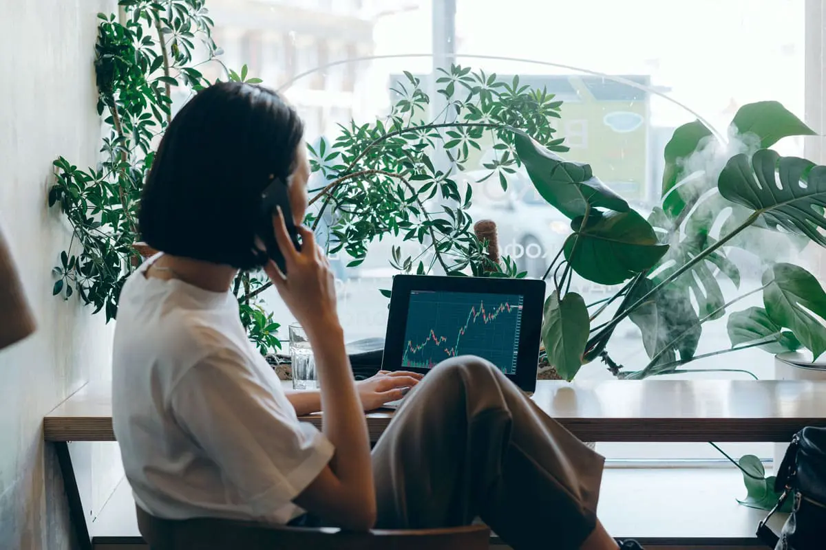 A woman is watching a stock ticker and using her phone
