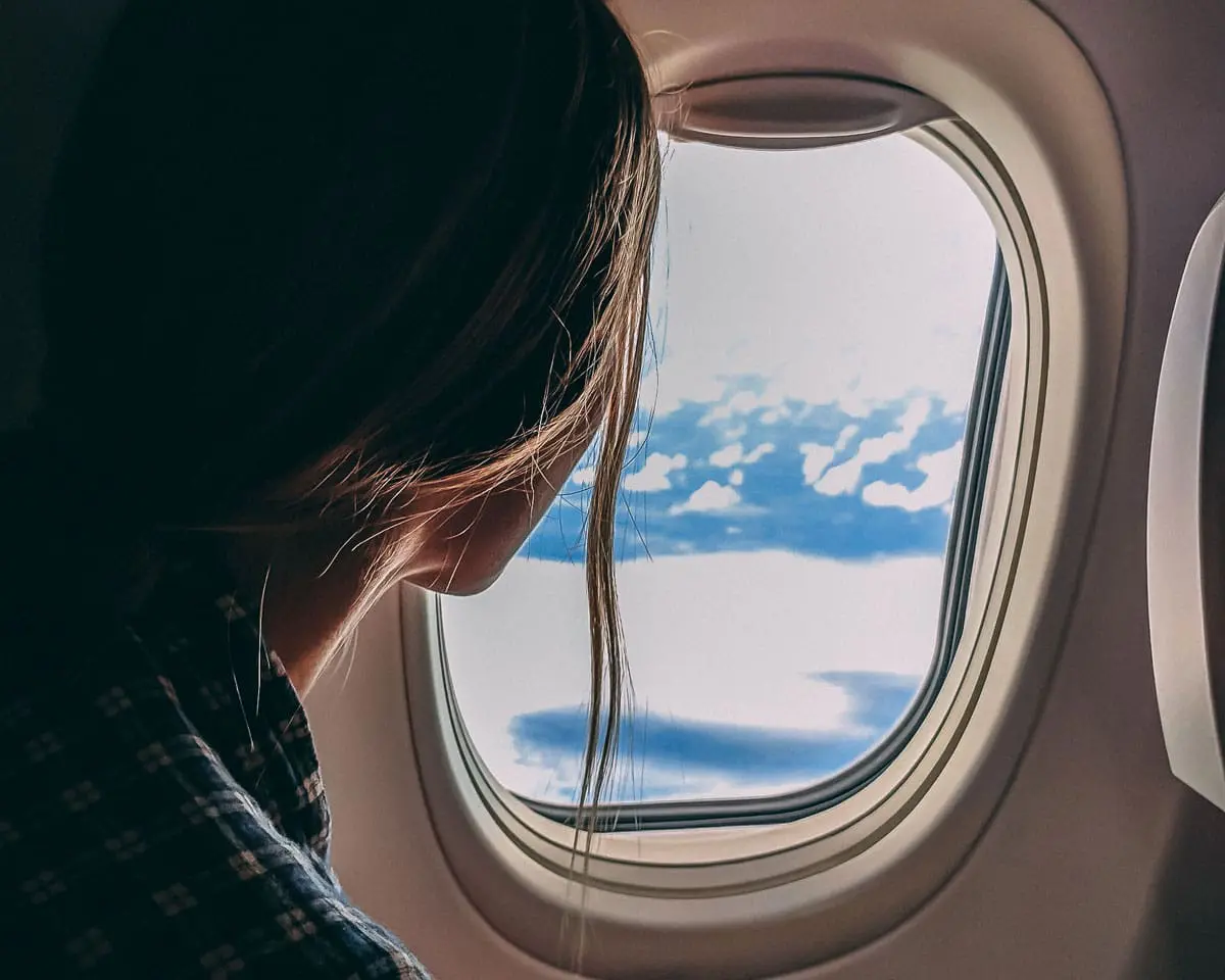 A woman is looking out of the window of an airplane