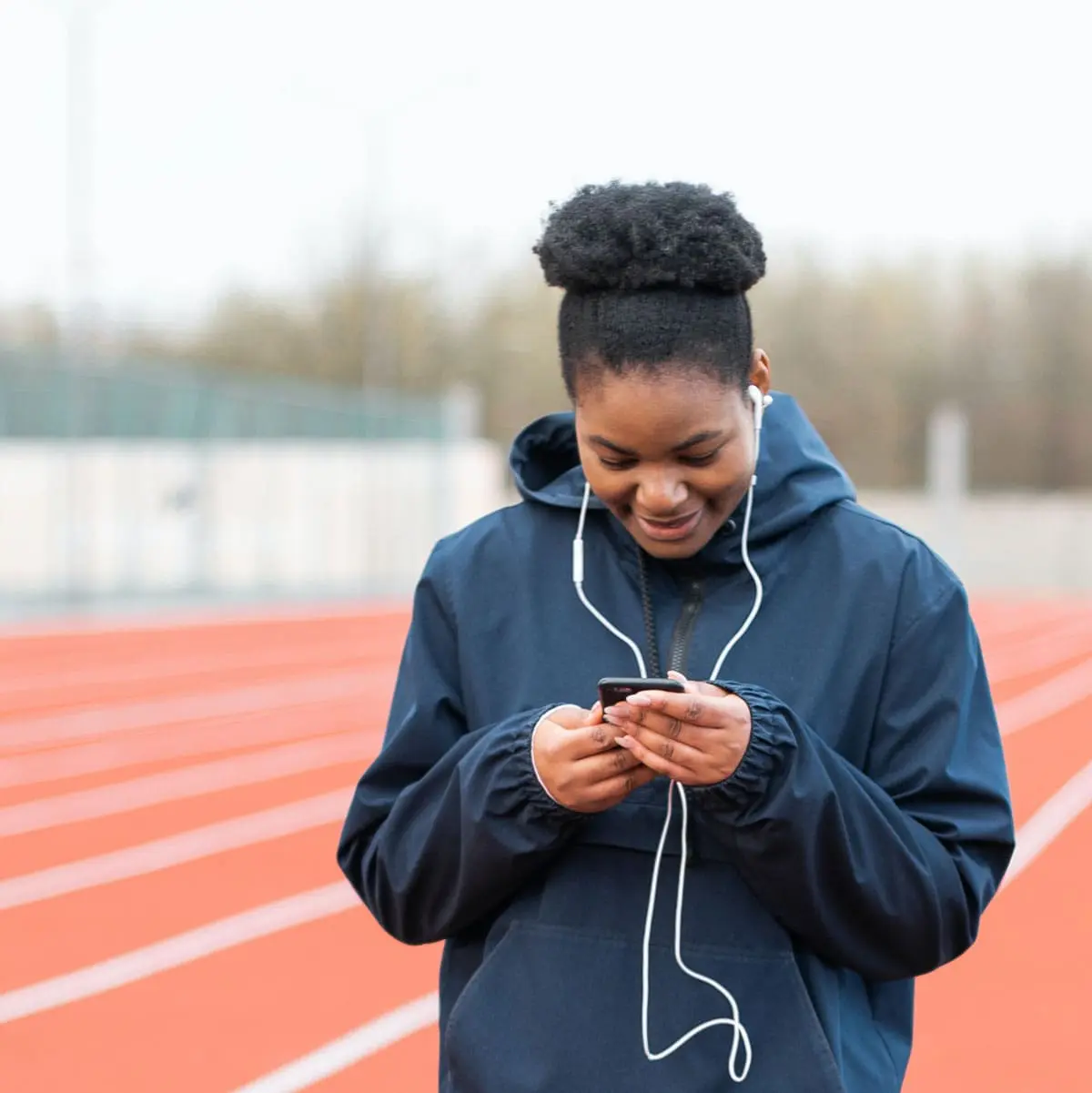 A woman wearing ear buds and using her phone