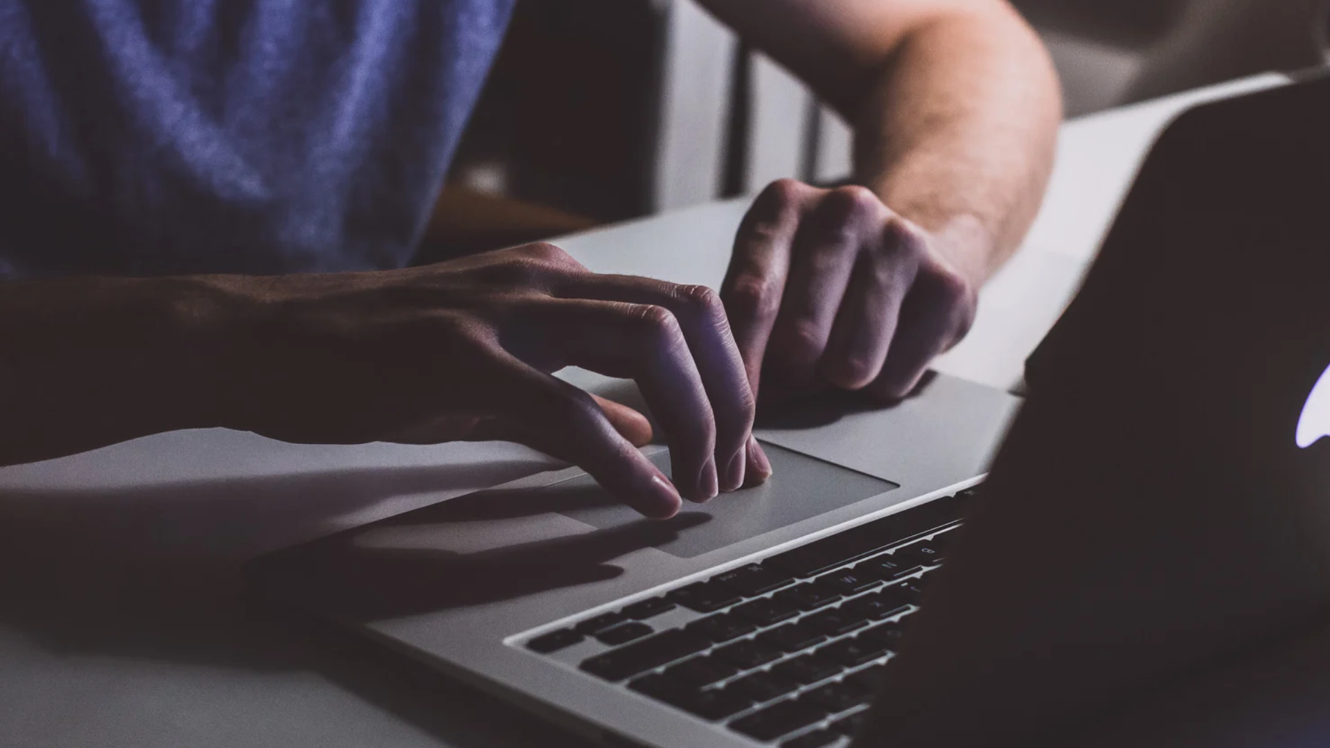 A credit union member typing on a laptop, monitoring their accounts for suspicious activity.