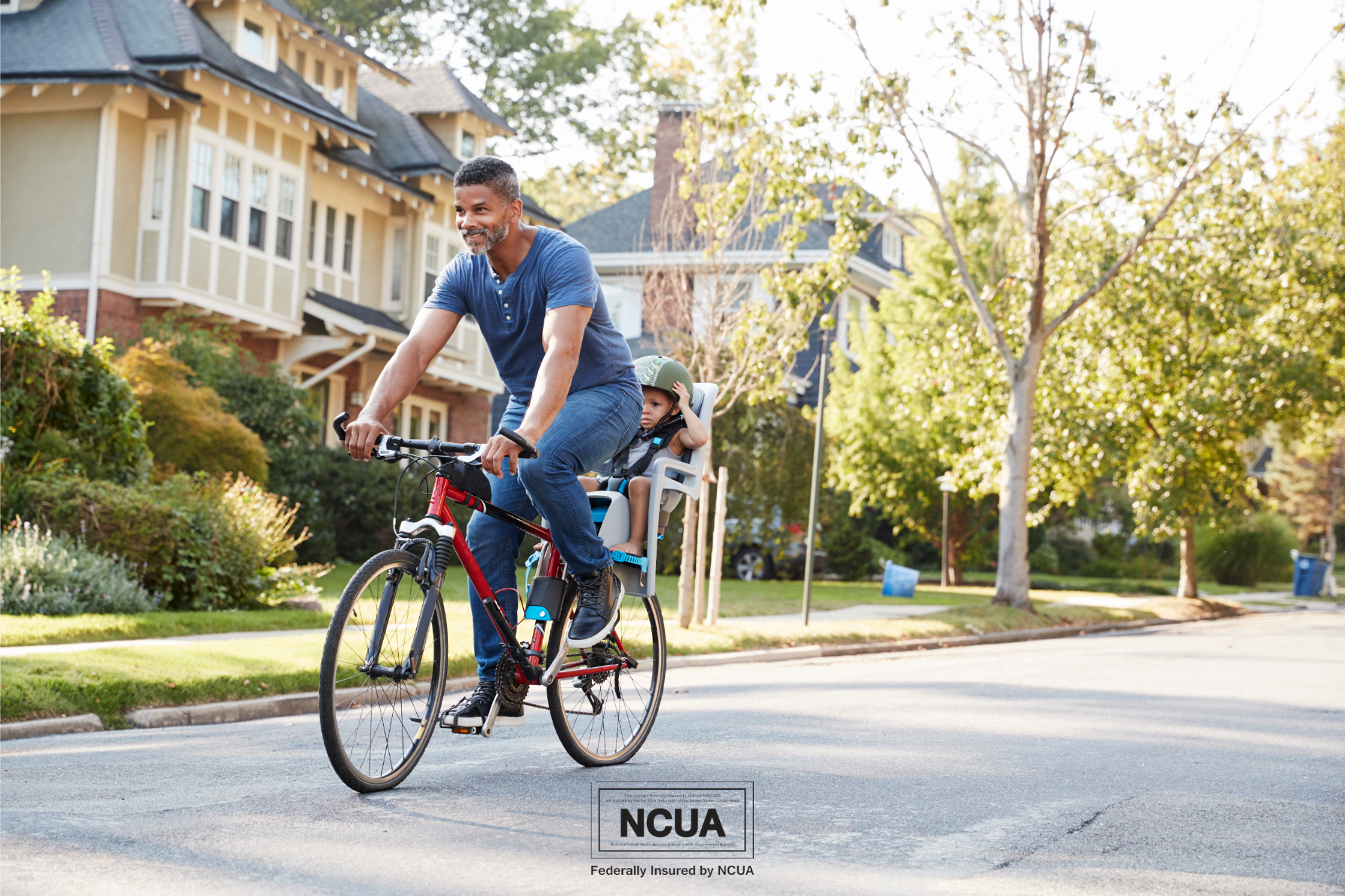 It's not too late to make financial resolutions for the new year. In this image, a man rides his bicycle in a residential neighborhood with his child in a child seat behind him. Buying a bike is one way to save money on gasoline expenses.