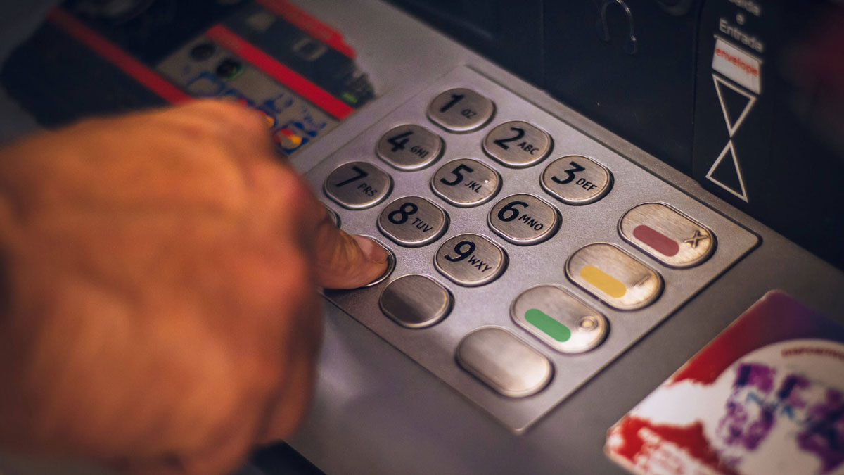 A man is entering his PIN into an ATM