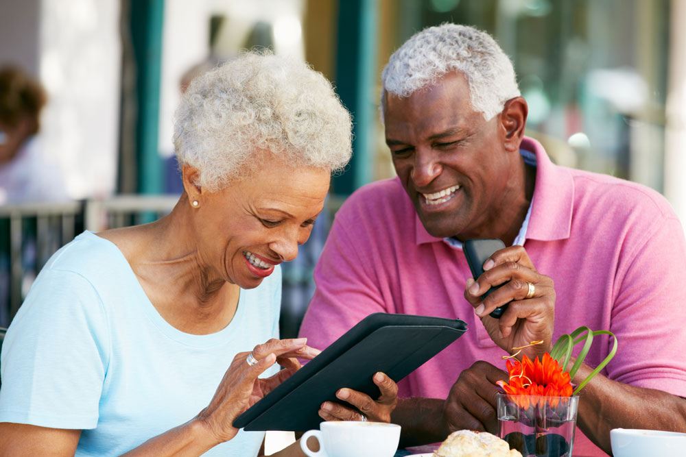 An older couple is smiling using a tablet together