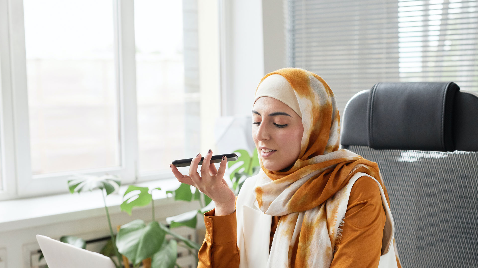 A woman wearing an orange hijab is on speakerphone