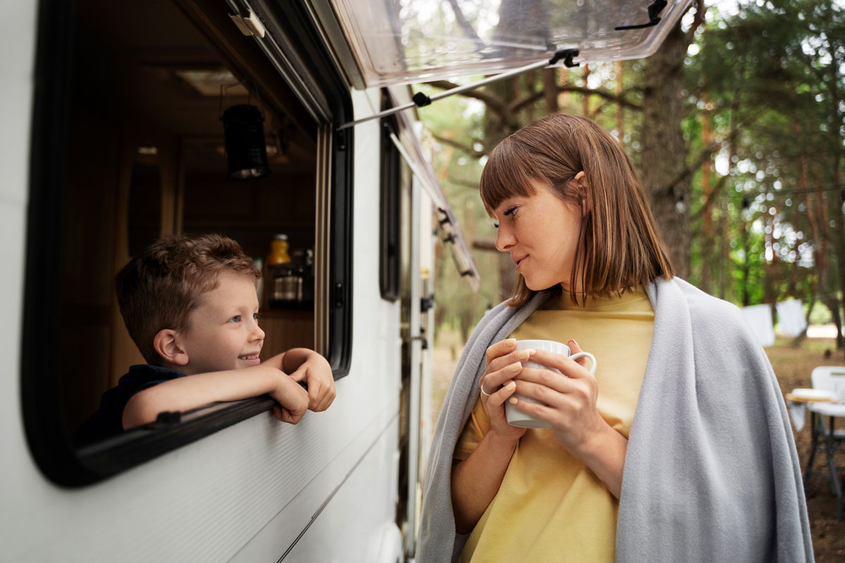 A woman and her child are talking to each other through the window of a recreational vehicle