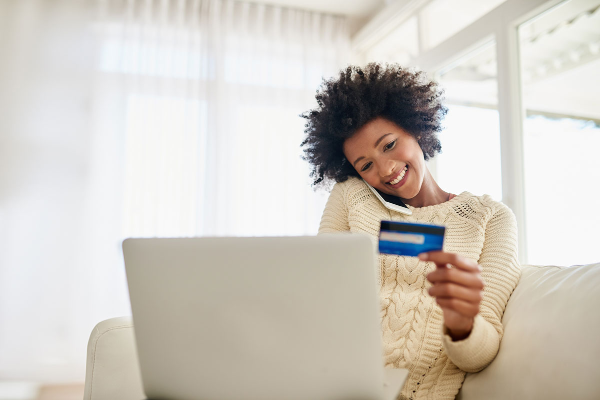A woman smiling while talking on the phone and holding a debit card