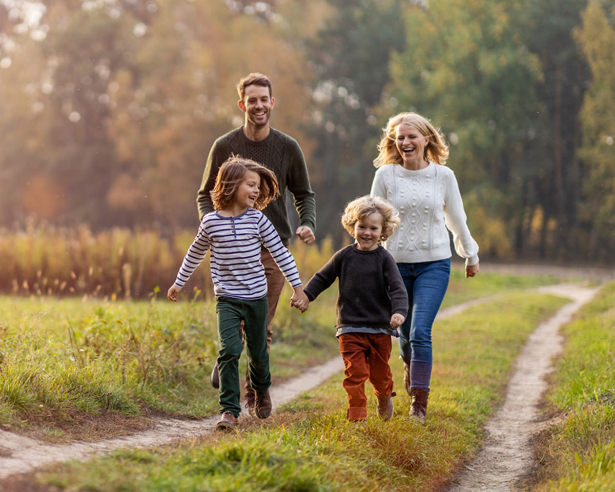 Family smiling and running through a field together