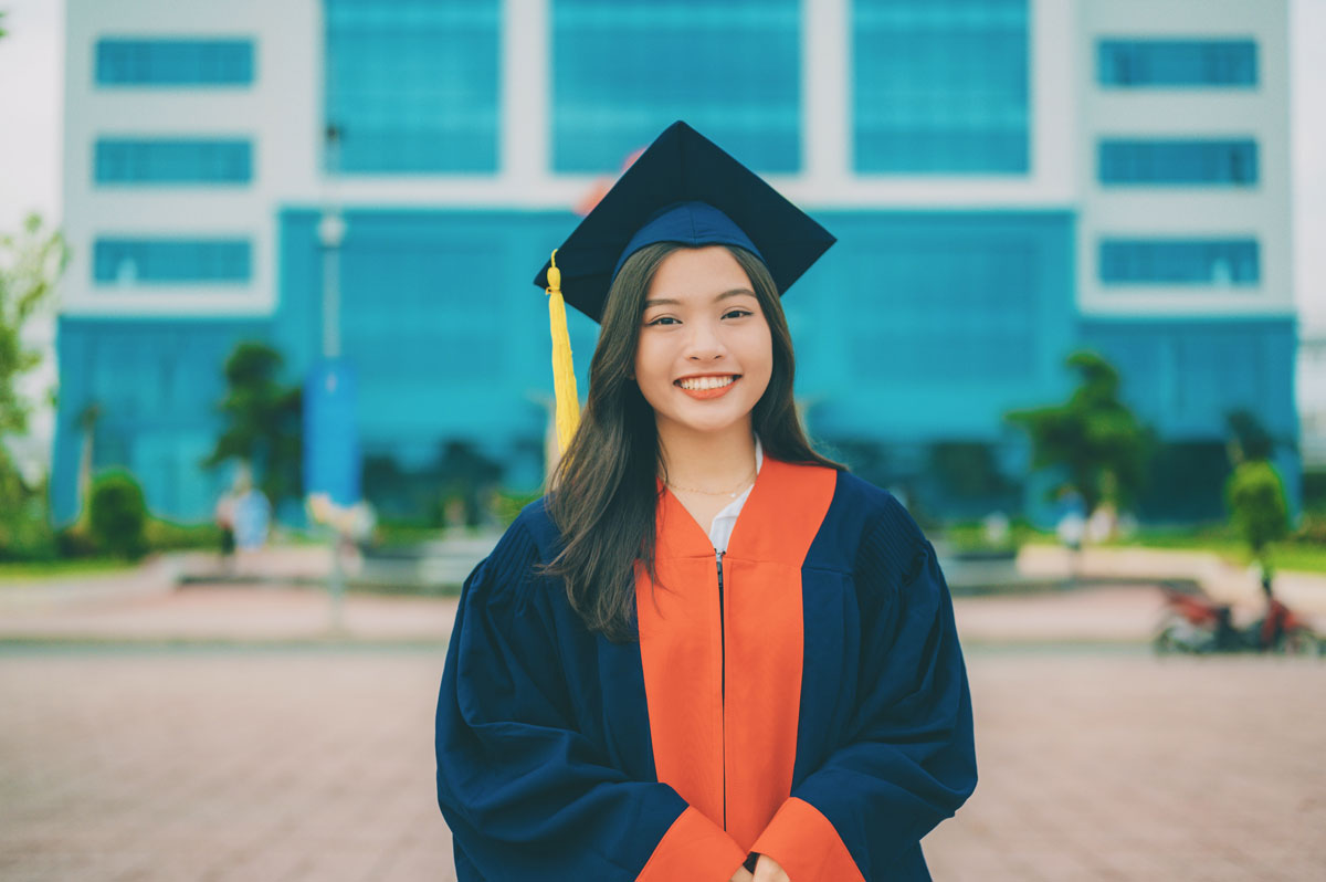 A young woman is smiling for the camera wearing a navy blue cap and gown