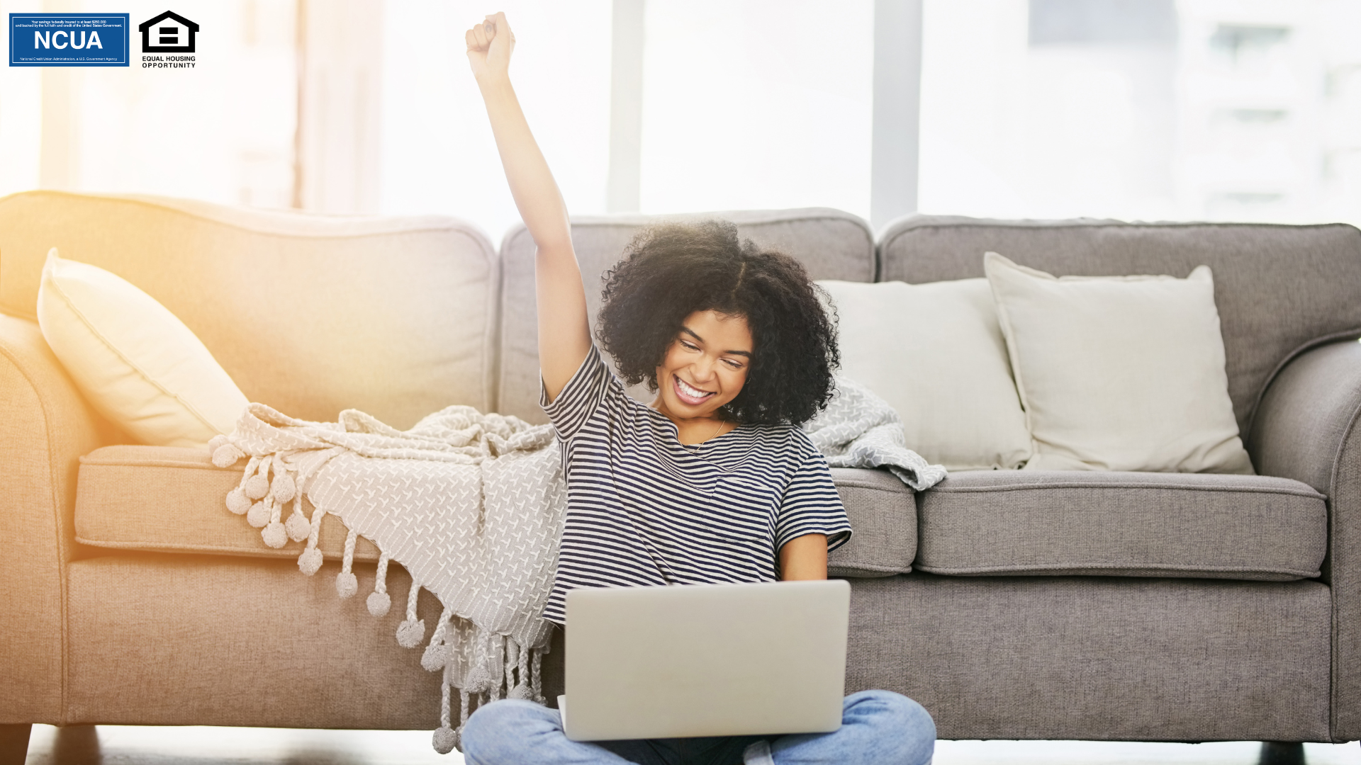 A person sitting on the floor with computer with her hand up