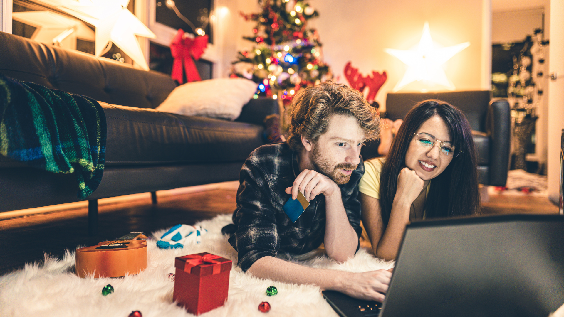 A person and person lying on the floor looking at a computer